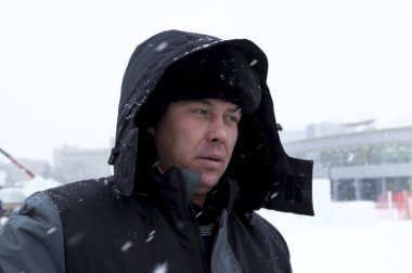 Kafasında başlığı olan, kışlık takım elbiseli bir müteahhit portresi.