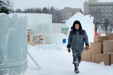 Kafasında başlığı olan, kışlık takım elbiseli bir müteahhit portresi.
