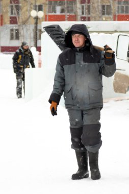 İnşaat işçisi buz kasabasından kar temizliyor.