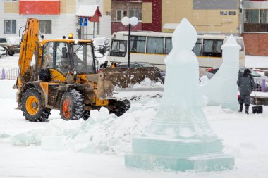 İnşaat işçisi buz kasabasından kar temizliyor.