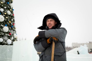 İnşaat işçisi buz kasabasından kar temizliyor.