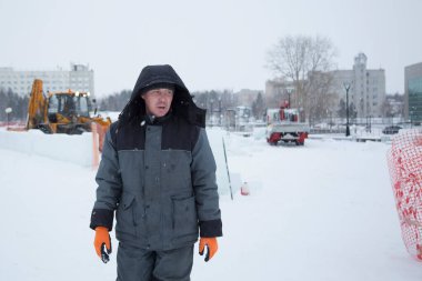 Kafasında başlığı olan, kışlık takım elbiseli bir müteahhit portresi.