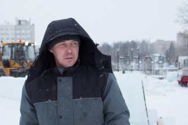 Kafasında başlığı olan, kışlık takım elbiseli bir müteahhit portresi.