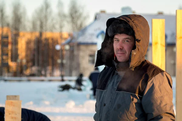 Kafasında başlığı olan, kışlık takım elbiseli bir müteahhit portresi.