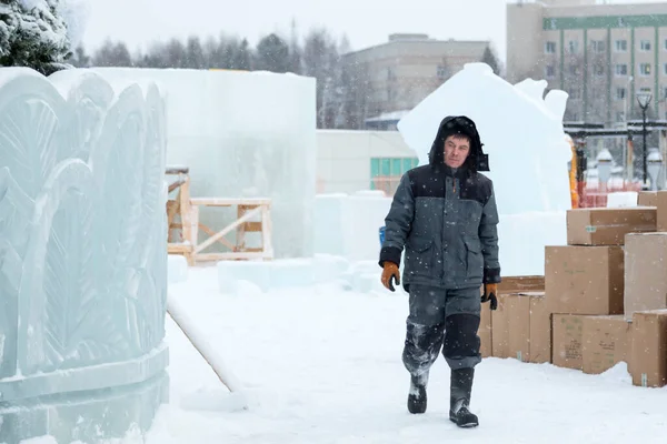 Kafasında başlığı olan, kışlık takım elbiseli bir müteahhit portresi.