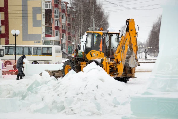 İnşaat işçisi buz kasabasından kar temizliyor.