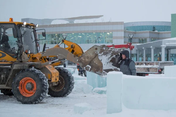İnşaat işçisi buz kasabasından kar temizliyor.