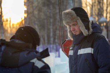 Kış tulumları ve buz kasabasının toplantı yerinde kulaklık takan bir şapka.