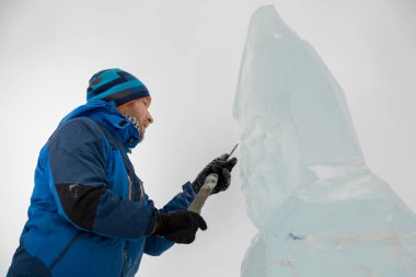 Heykeltıraş Noel için buz kalıbından bir buz heykeli kesiyor.