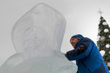 Heykeltıraş bir buz figür Noel ağacı arka planı buz kalıbı bir keski ile keser