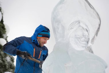 Heykeltıraş Noel için buz kalıbından bir buz heykeli kesiyor.