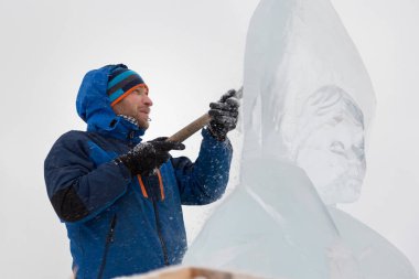 Heykeltıraş, buzdan bir heykeli Noel için keskiyle kesiyor.