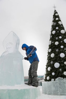 Heykeltıraş bir buz figür Noel ağacı arka planı buz kalıbı bir keski ile keser