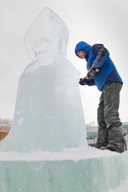 Heykeltıraş, bir buz kalıbından bir buz figürünü kesiyor ve İsa için bir keski ile ahşap bir iskelenin üzerinde duruyor.