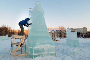Heykeltıraş, bir buz kalıbından bir buz figürünü kesiyor ve İsa için bir keski ile ahşap bir iskelenin üzerinde duruyor.