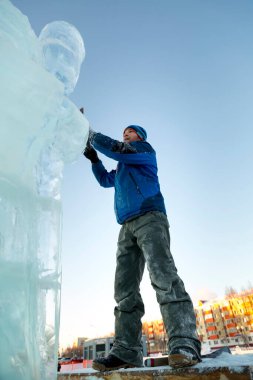 Heykeltıraş, bir buz kalıbından bir buz figürünü kesiyor ve İsa için bir keski ile ahşap bir iskelenin üzerinde duruyor.