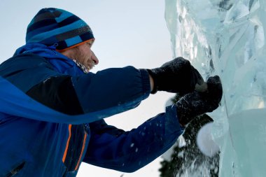 Heykeltıraş, buzdan bir heykeli Noel için keskiyle kesiyor.