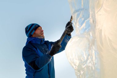 Heykeltıraş, buzdan bir heykeli Noel için keskiyle kesiyor.