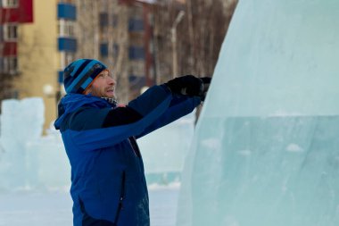 Heykeltıraş Noel için buz kalıbından bir buz heykeli kesiyor.