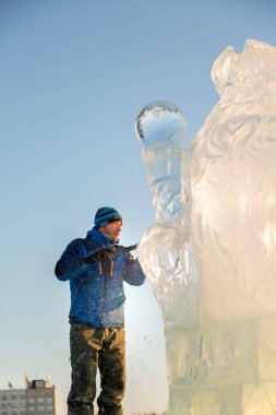 Heykeltıraş, bir buz kalıbından bir buz figürünü kesiyor ve İsa için bir keski ile ahşap bir iskelenin üzerinde duruyor.