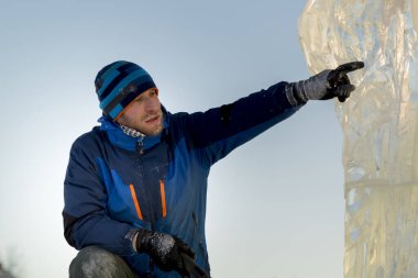 Heykeltıraş Noel için buz kalıbından bir buz heykeli kesiyor.