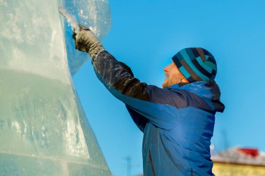 Heykeltıraş Noel için buz kalıbından bir buz heykeli kesiyor.
