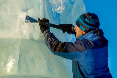 Heykeltıraş Noel için buz kalıbından bir buz heykeli kesiyor.