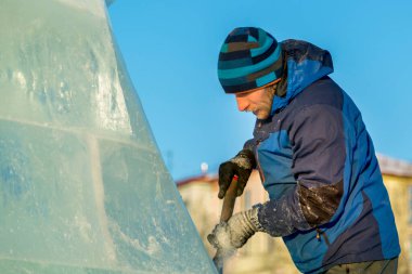 Heykeltıraş Noel için buz kalıbından bir buz heykeli kesiyor.