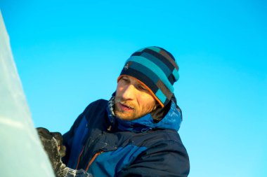 Heykeltıraş, buzdan bir heykeli Noel için keskiyle kesiyor.