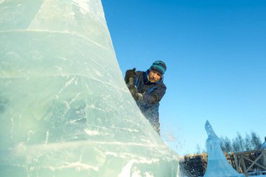 Heykeltıraş Noel için buz kalıbından bir buz heykeli kesiyor.