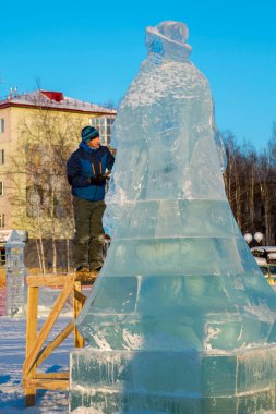 Heykeltıraş, bir buz kalıbından bir buz figürünü kesiyor ve İsa için bir keski ile ahşap bir iskelenin üzerinde duruyor.