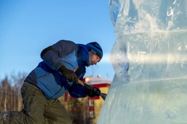 Heykeltıraş Noel için buz kalıbından bir buz heykeli kesiyor.