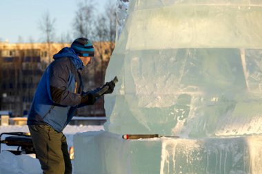 Heykeltıraş Noel için buz kalıbından bir buz heykeli kesiyor.