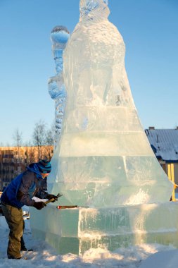 Heykeltıraş Noel için buz kalıbından bir buz heykeli kesiyor.