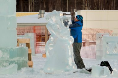 Heykeltıraş Noel için buz kalıbından bir buz heykeli kesiyor.