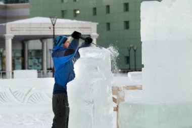 Heykeltıraş Noel için buz kalıbından bir buz heykeli kesiyor.