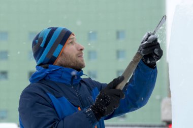 Heykeltıraş, buzdan bir heykeli Noel için keskiyle kesiyor.