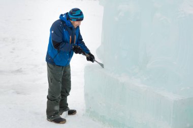 Heykeltıraş buz duvarına keskiyle desenler oyuyor.