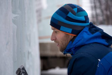 Heykeltıraş buz duvarına keskiyle desenler oyuyor.