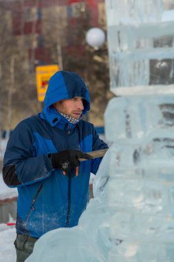 Heykeltıraş Noel için buz kalıbından bir buz heykeli kesiyor.