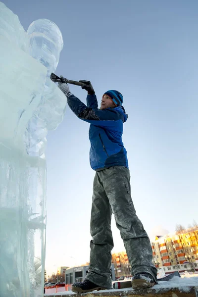 雕塑家用凿子从冰块上切下一个冰人 因为克莉丝汀在木制脚手架上 — 图库照片