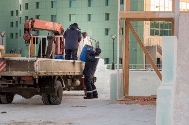 Buz kasabasının şantiyesindeki tesisatçı varili bir kamyonun arkasından boşaltıyor.