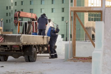 Buz kasabasının şantiyesindeki tesisatçı varili bir kamyonun arkasından boşaltıyor.