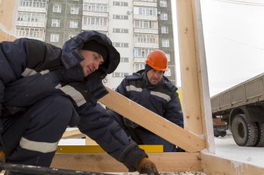 İşçiler ahşap bir kaydırağın ahşap kirişini düzleştiriyorlar.