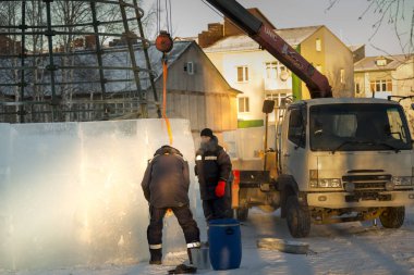 Buz kasabasının inşaatçıları Noel ağacını yüksek yeşil panellerle çevrelediler.