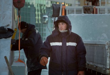 İki işçi, ahşap bir kaydırağın çerçevesini buz panelleriyle kaplıyor.