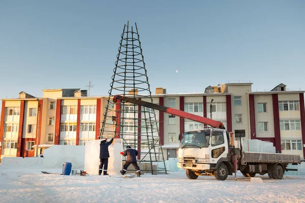 氷の町の建築家は 高い緑のパネルで建設中のクリスマスツリーを囲みます — ストック写真