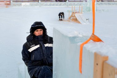 Buz kalıbı montajında mavi kapüşonlu ceketli bir tesisatçı.