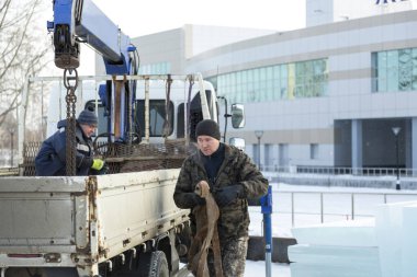 Kışlık ceketli bir işçinin portresi ve elinde bant sapıyla örülmüş siyah bir şapka.