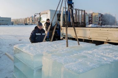 İki toplayıcı işçi, buz kasabasının inşaat sahasında buz tabakaları depoluyorlar.